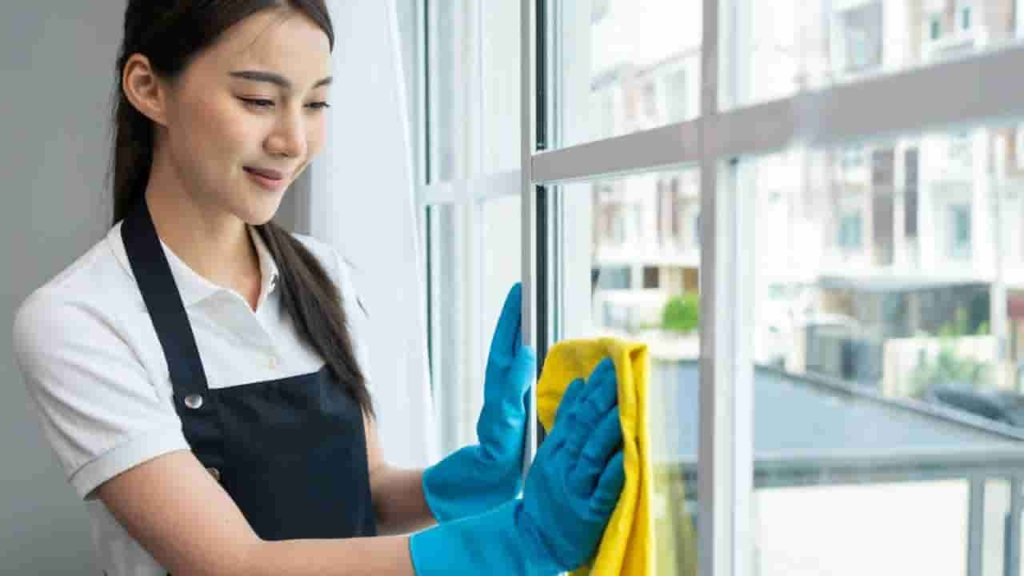 Professional house cleaning services in Singapore - maid wiping window frame.